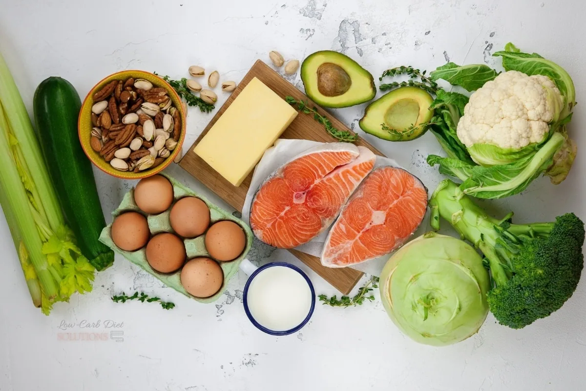 Keto macro foods laid out: salmon, eggs, cheese, avocado, nuts and low-carb vegetables
