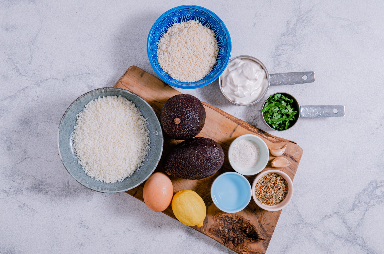 Ingredients for garlic parmesan baked avocado fries with lemon dip arranged on a cutting board before preparation