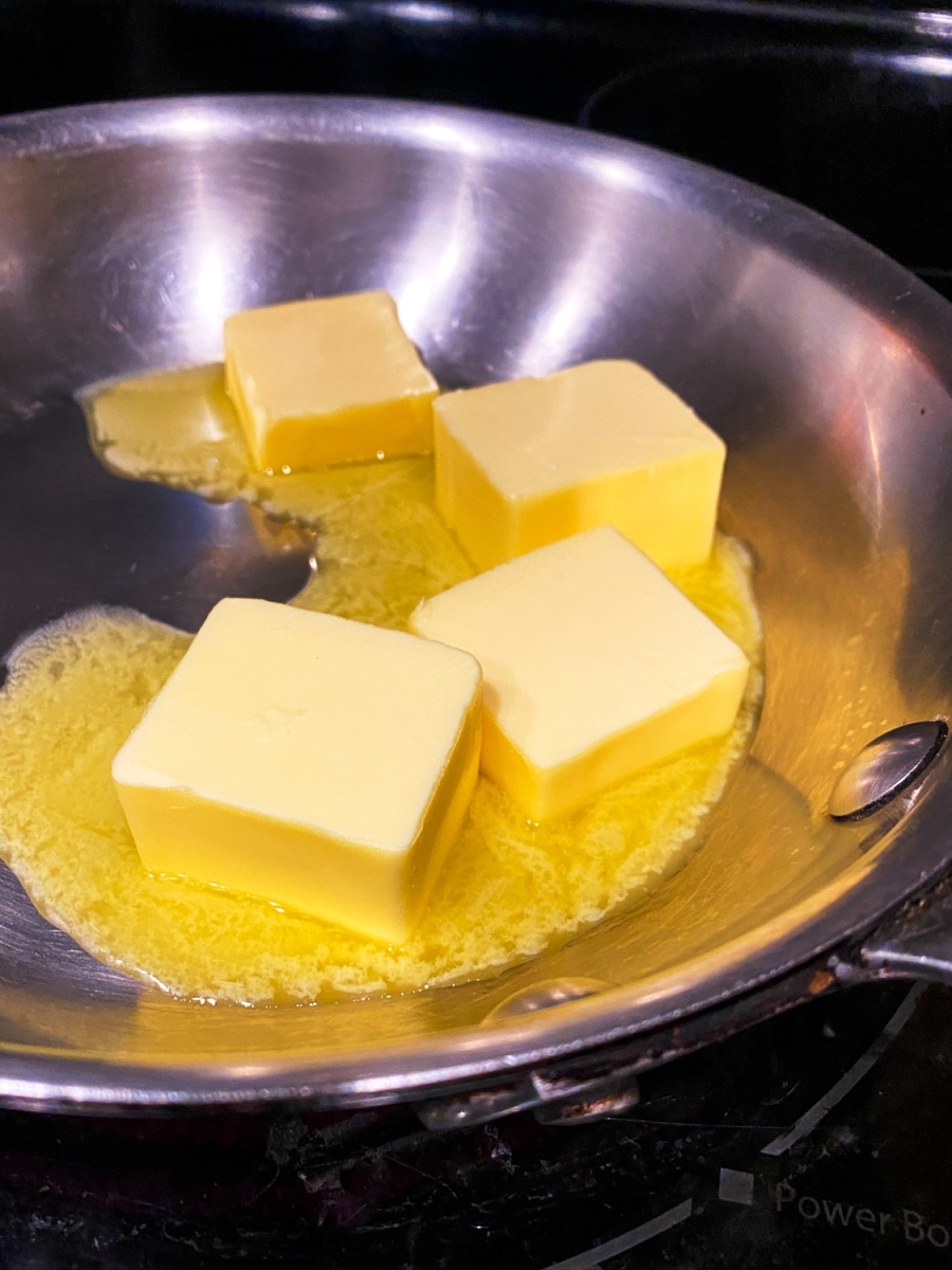 cubes of unsalted butter melting in a skillet for keto eggs benedict with spinach