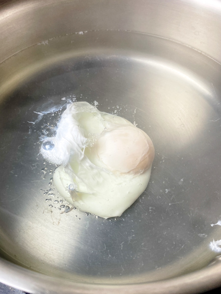 poached egg with set whites and soft runny yolk in simmering water