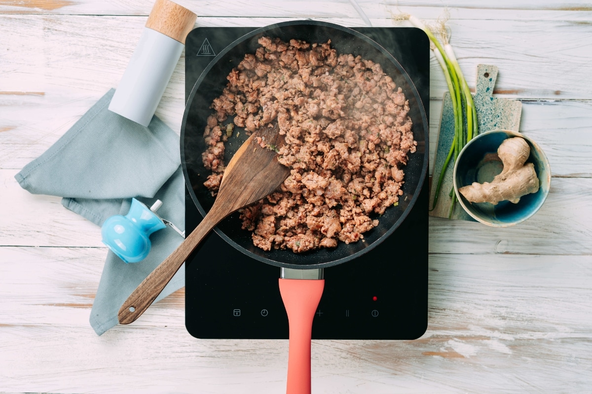 Browned pork sausage cooking in a skillet for low-carb egg roll in a bowl recipe